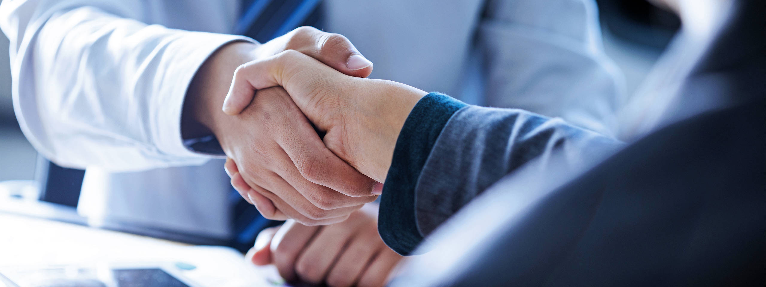 Two hands shake in a business setting, symbolising agreement and cooperation.