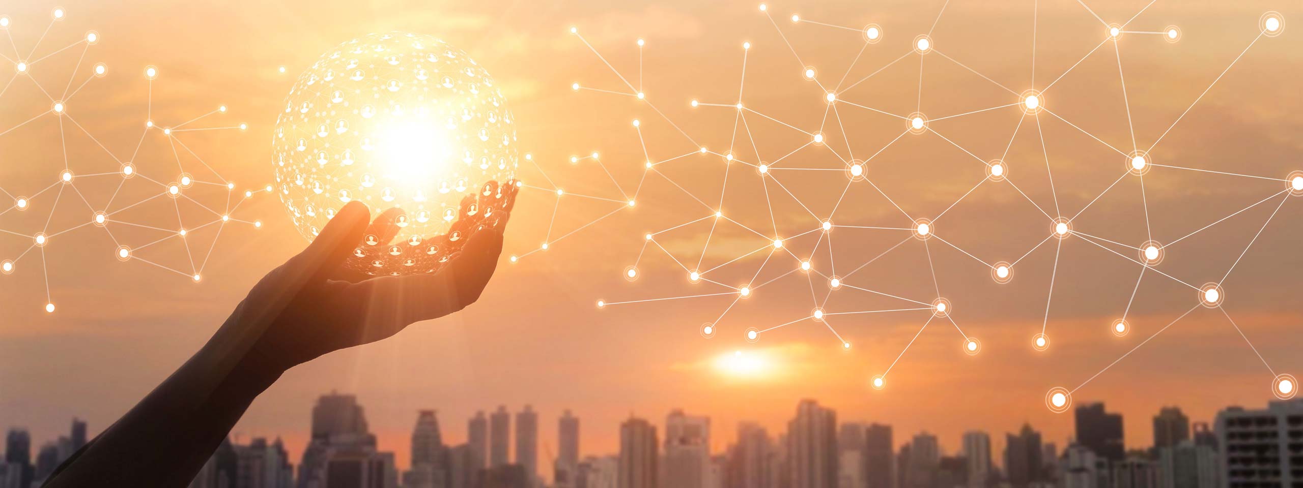 A hand holds a glowing sphere against a sunset city skyline, with connected dots symbolising networks.
